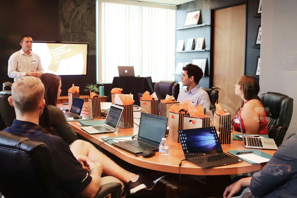 A hiring team meeting around a boardroom table with laptops