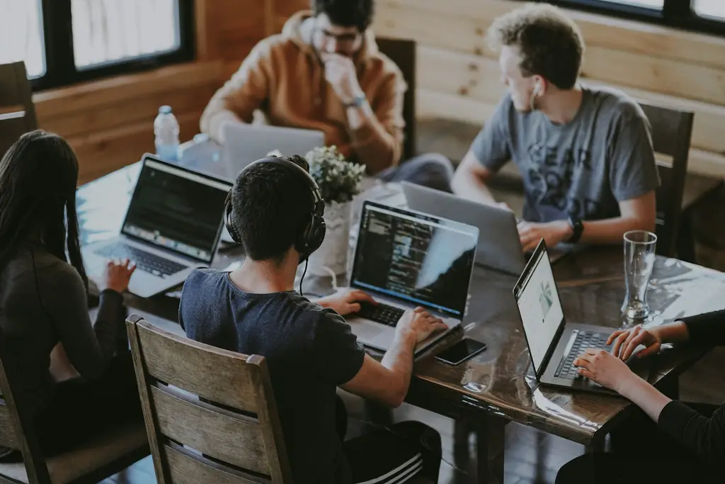 A team collaborating around a shared table with laptops